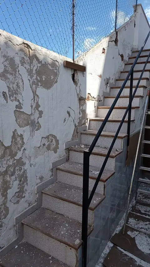 Muro de escalera con la pintura levantada antes de repararlo