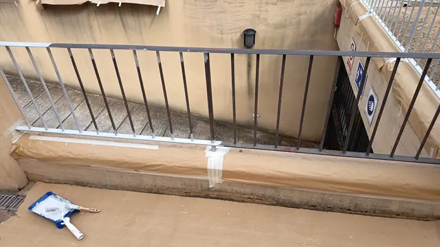 Barandilla de rampa de garaje a medio pintar con el muro protegido con papel